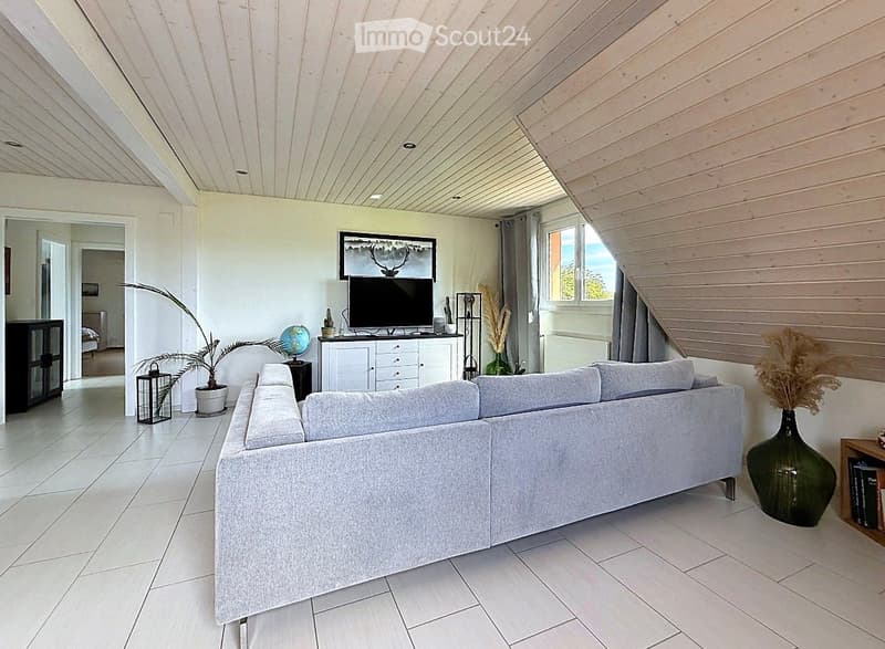 Modern living room with a grey sectional sofa, flat-screen TV, globe, decorative vases, and a large window with curtains.