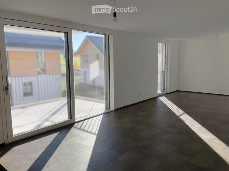 Empty room with tiled floor, large sliding glass door, and white walls.