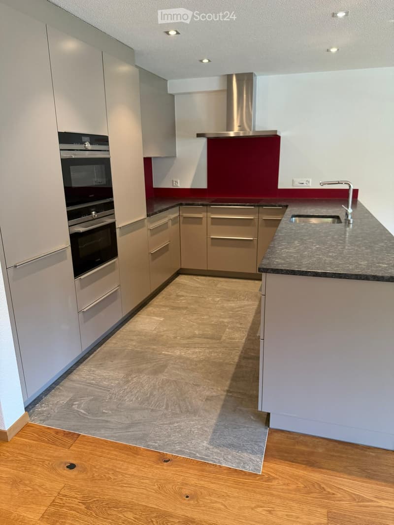 Modern kitchen with white cabinets, stainless steel oven, granite countertop, and a sink with a modern faucet.