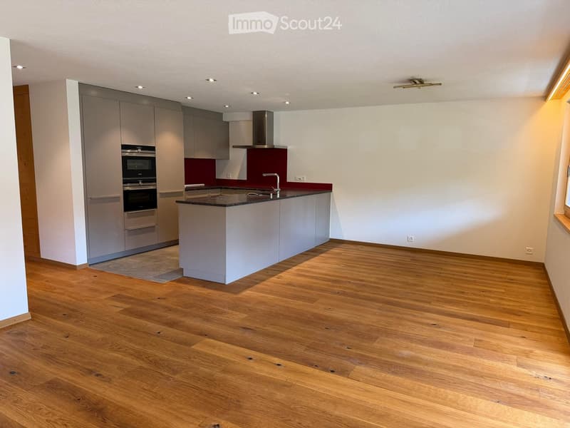 Modern kitchen with light-colored cabinets, stainless steel appliances, and a central island with a dark countertop.