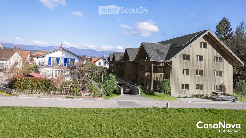 Building complex, modern architecture, beige and brown exterior, underground garage, parking area in front.