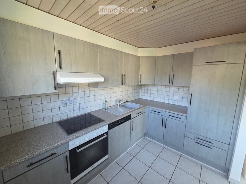 Modern kitchen with light wood cabinets, granite countertops, and stainless steel appliances including an oven, dishwasher, and range hood. The sink has a modern faucet, and the floor is tiled.