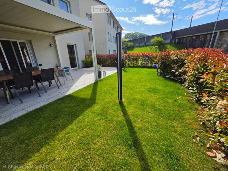 Well-maintained garden with green lawn, trimmed bushes, and a patio area with a table and chairs.