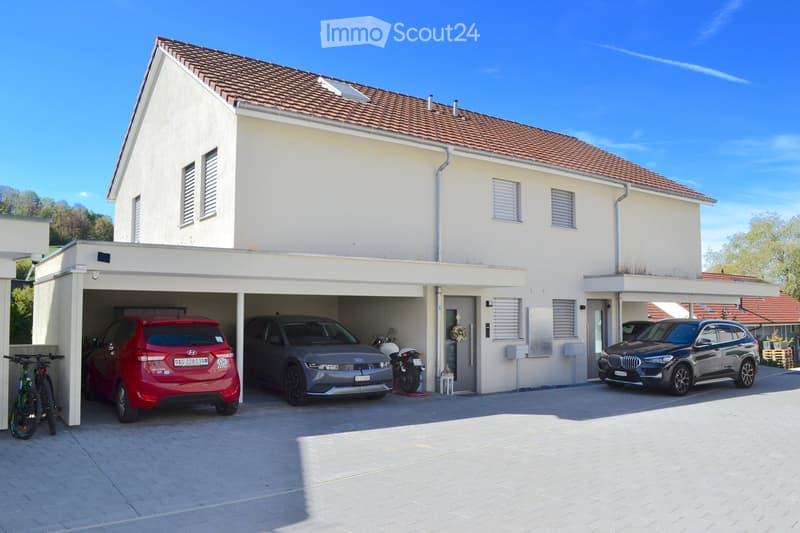 Two-story house with a red-tiled roof, white exterior, and attached garage housing multiple vehicles including a red SUV, a grey SUV, a black BMW, and a motorcycle.