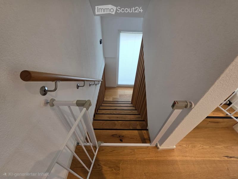 Wooden staircase with a wooden handrail and white safety gate, leading to a bright room with large windows and wooden flooring.