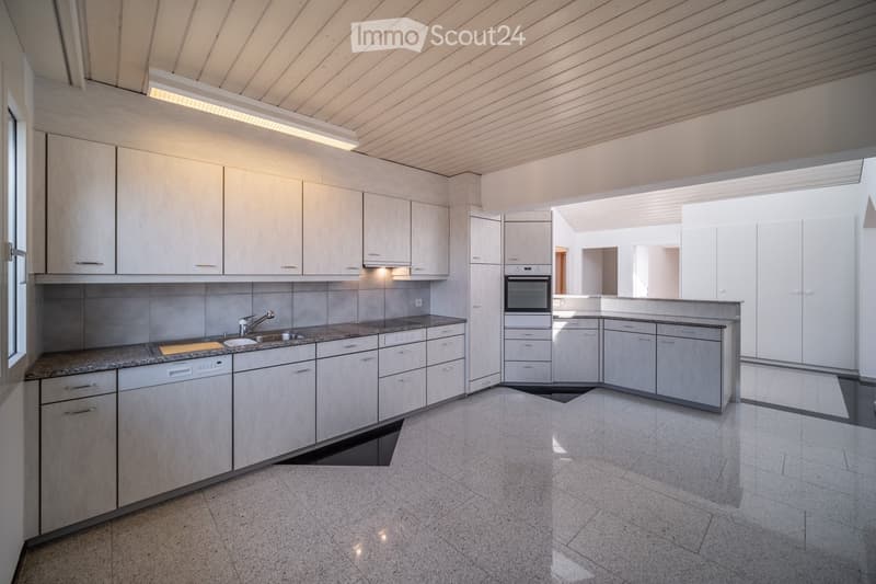 Modern kitchen with light wood cabinets, granite countertops, and stainless steel appliances including a sink, faucet, oven, and dishwasher.