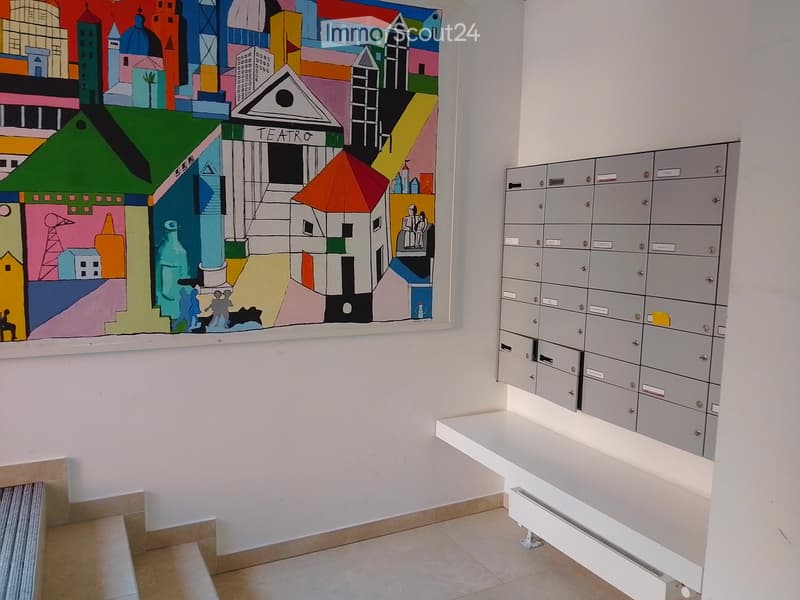 A hallway with a colorful mural depicting a cityscape and a row of mailboxes on the right side.