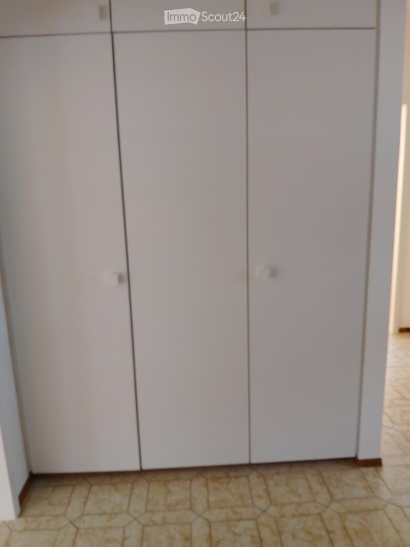 Empty room with white cabinets and tiled floor.