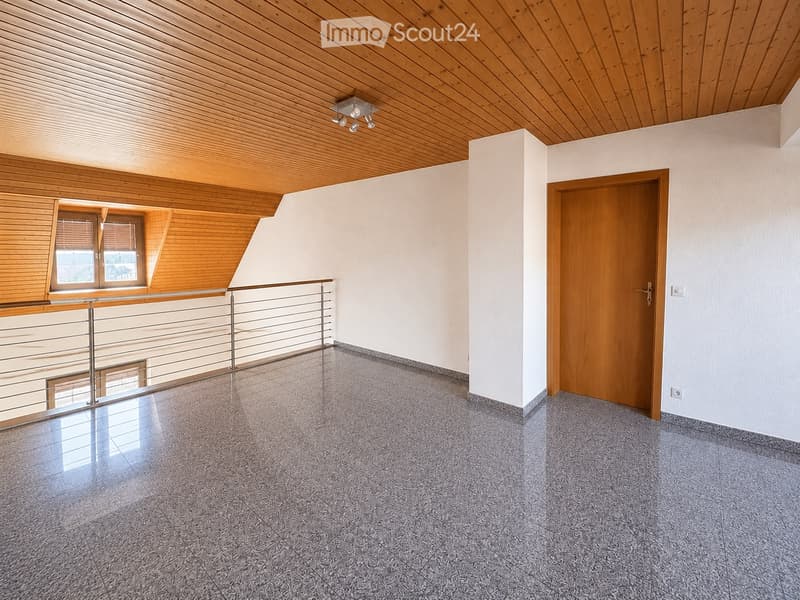Empty room with wooden ceiling, tiled floor, white walls, and a wooden door. Features a metal railing and a window with blinds.