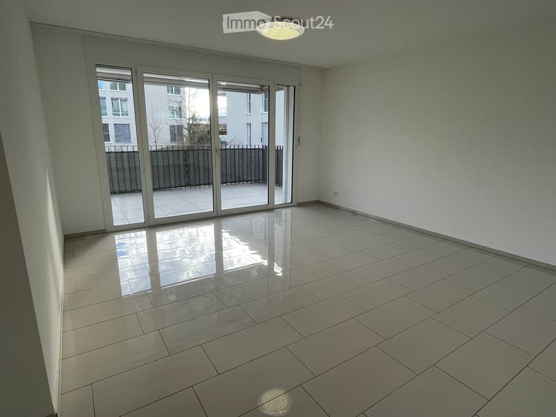 Empty room with tiled floor, large sliding glass doors leading to a balcony, and a ceiling light fixture.