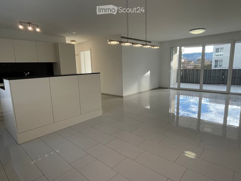 Empty kitchen with white tiled floor, modern cabinetry, and large sliding glass doors leading to a balcony.