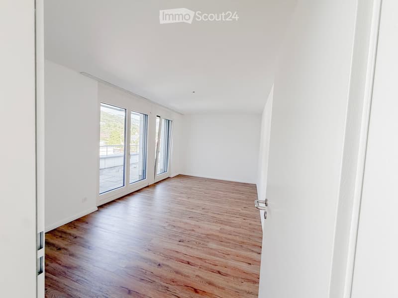 Empty room with light wooden flooring, white walls, and large glass sliding doors leading to a balcony.