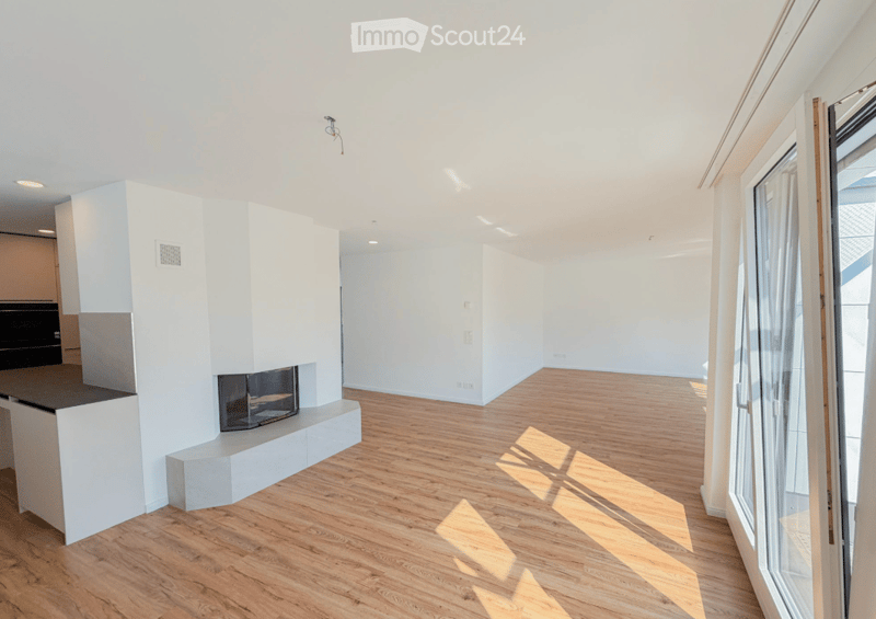 Empty room with white walls, wooden flooring, and large windows allowing natural light. No furniture or equipment present.