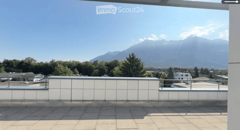 Roof terrace with a modern white railing, tiled floor, and panoramic mountain view.