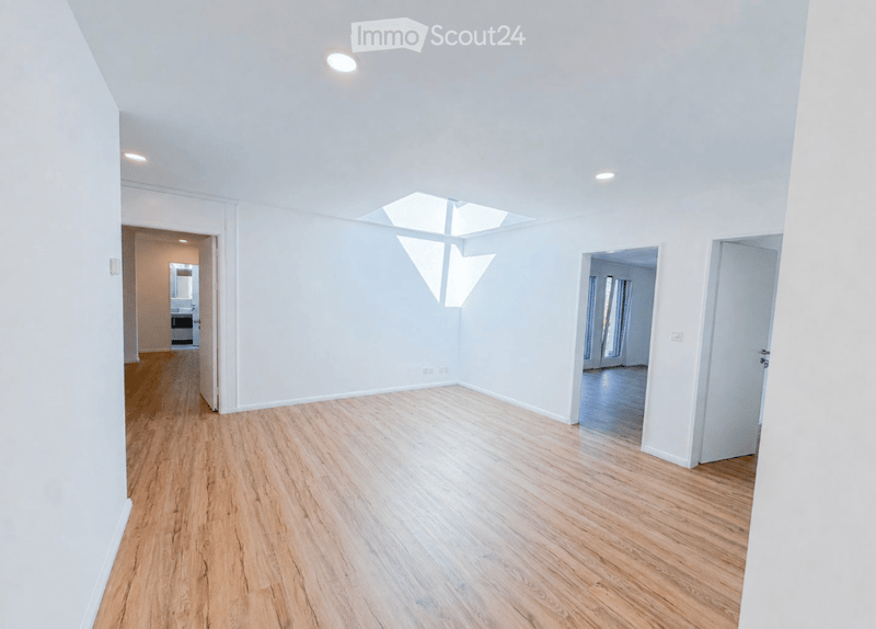 Empty room with light wooden flooring, white walls, and a skylight allowing natural light. No furniture or equipment is present.