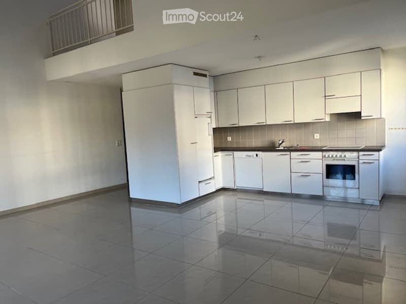 Modern, minimalist kitchen with white cabinets, a sink, and an oven. The space features a tiled floor and a balcony visible in the background.