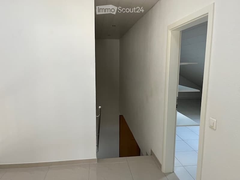 Empty hallway with white walls, tiled floor, and a staircase leading upwards.