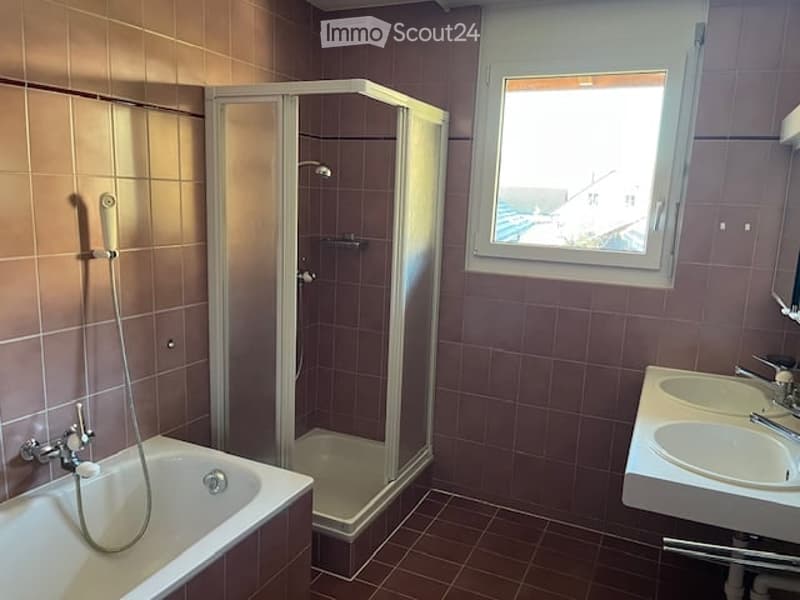 Bathroom with a bathtub, shower, double sink, and a window offering a view.