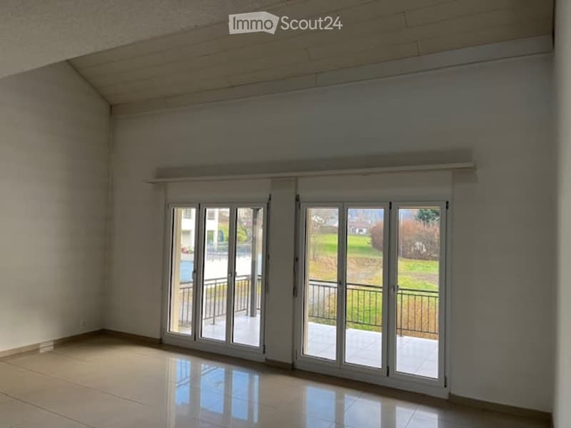 Empty room with large sliding glass doors leading to a balcony, tiled floor, and white walls.