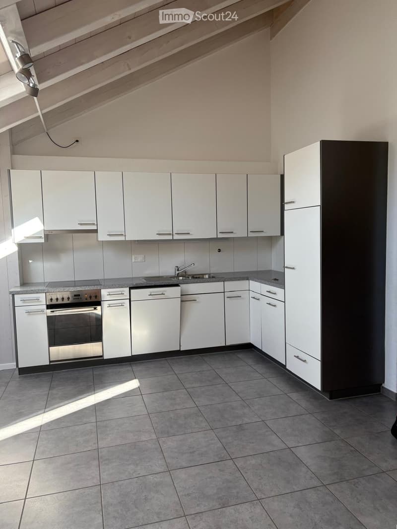 Modern kitchen with white cabinets, stainless steel oven, sink, and faucet, featuring tiled flooring and ample natural light.