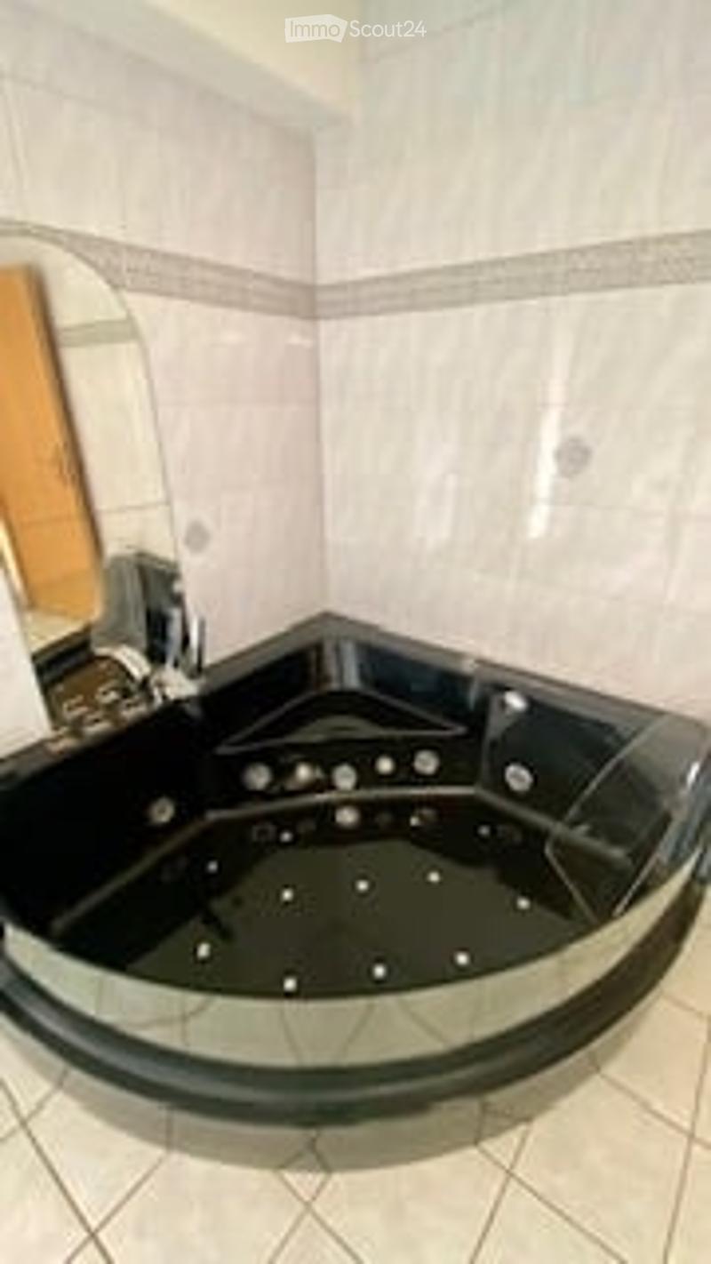Modern bathroom with a sleek black bathtub and a large mirror on the wall.