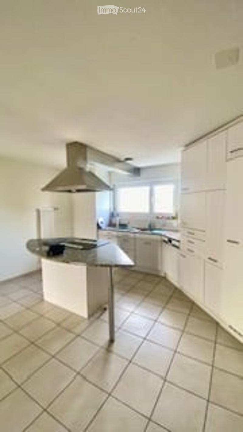 Modern kitchen with white cabinets, a central island, a stove, and a range hood. The floor is tiled, and there is a window providing natural light.