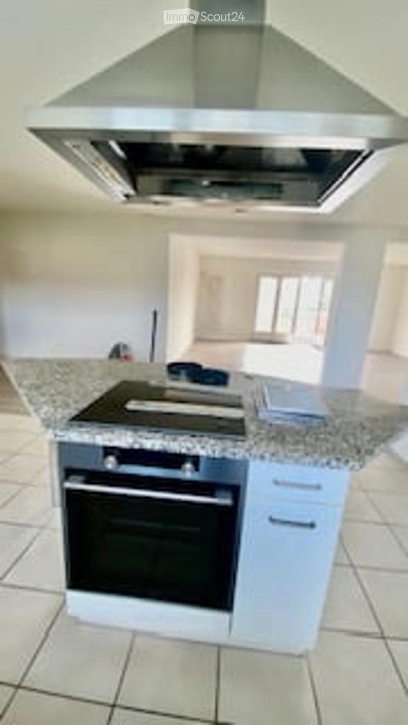 Modern kitchen with white cabinets, granite countertop, built-in stove, oven, and range hood.