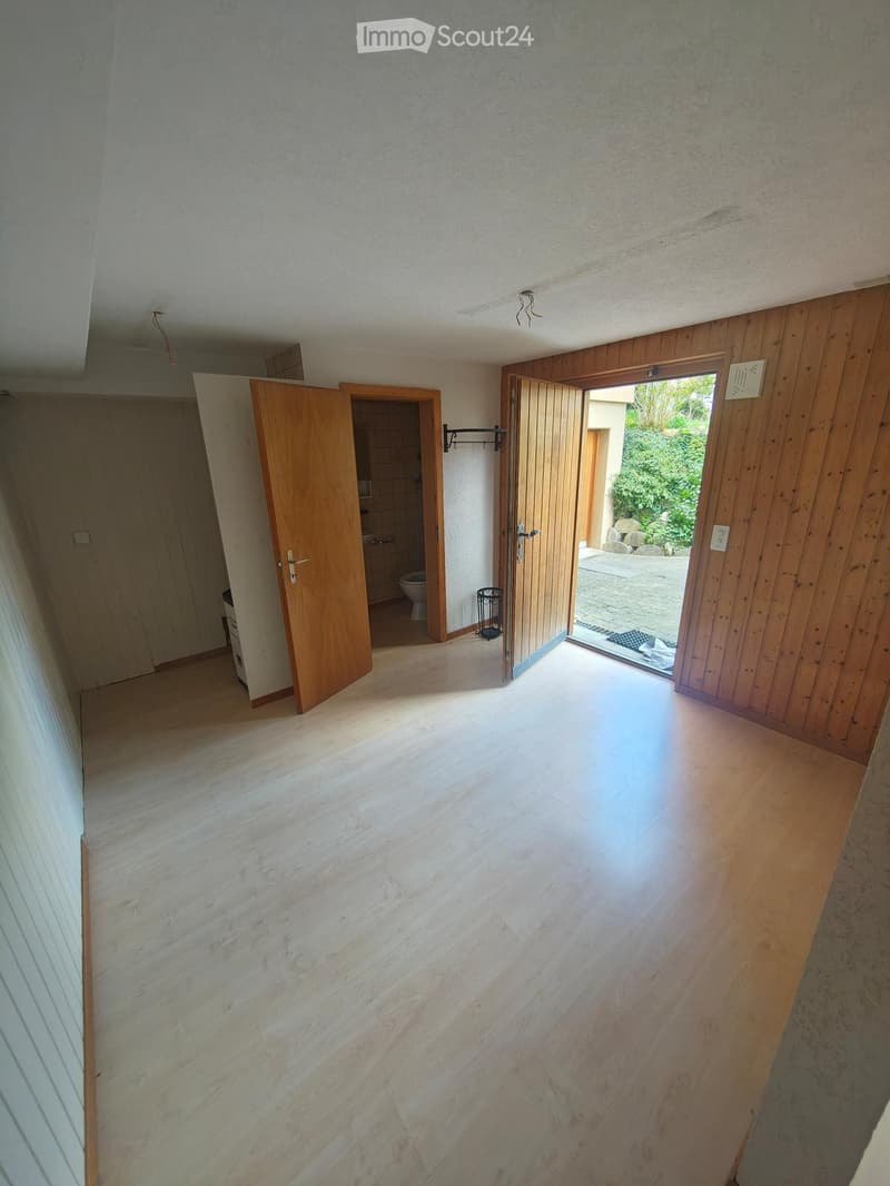 Empty hallway with wooden doors, marble flooring, and access to a bathroom and outdoor area.