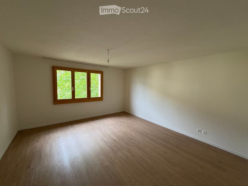 Empty room with wooden flooring, light-colored walls, and a window with wooden frames. The room is completely unfurnished, showing only the basic structure and natural light from the window.