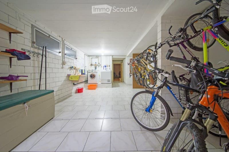 Storage area with multiple bicycles hanging on the wall, shelves with folded clothes, a bench, and a washing machine in the background.