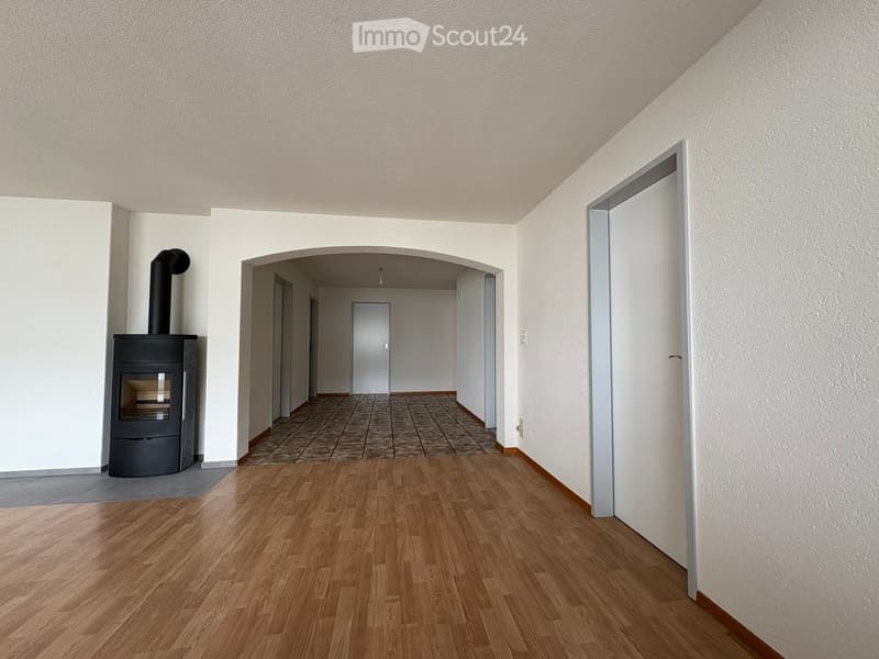 Empty hallway with wooden flooring, white walls, and a fireplace on the left side.