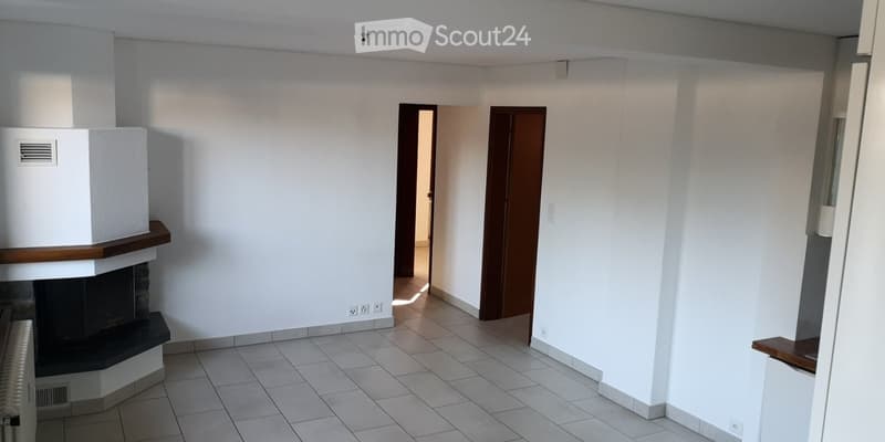 Empty hallway with tiled floor, white walls, and two doors leading to other rooms. A fireplace is visible on the left side.