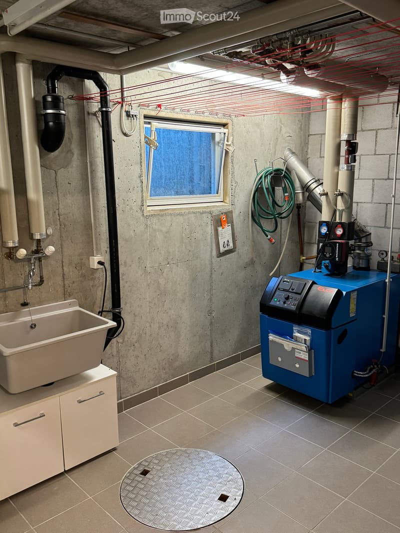 Utility room with a sink, cabinet, heating unit, and a window with a view of the outside.