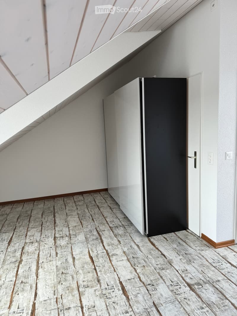Modern hallway with white walls, wooden trim, and a newspaper-themed floor. Features a black door and a white door frame.