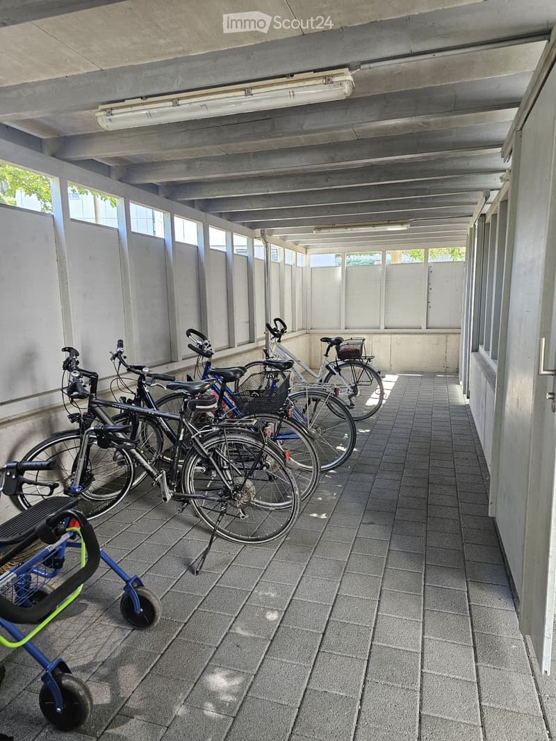Covered outdoor area with tiled floor, several bicycles parked, and a stroller visible.