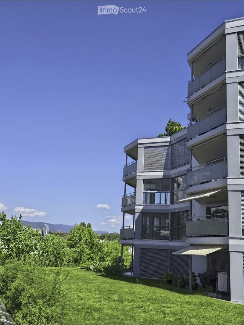 Modern two-story house with balconies, large windows, and a well-maintained lawn in front.
