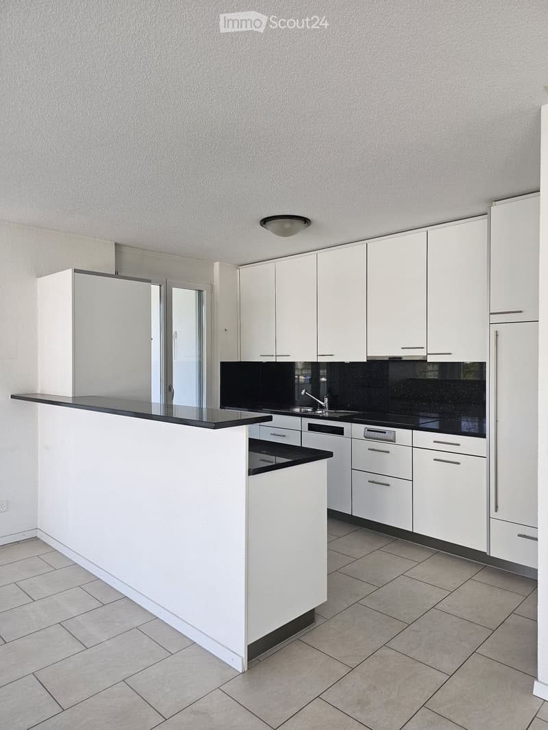 Modern kitchen with white cabinets, black countertop, and built-in appliances including a sink and faucet.