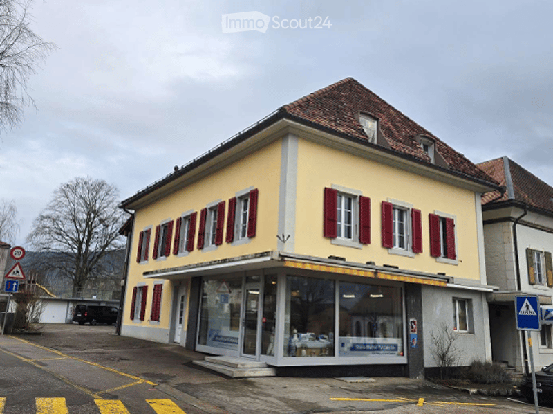 2 story building, yellow exterior, red shutters, glass storefront, parking lot