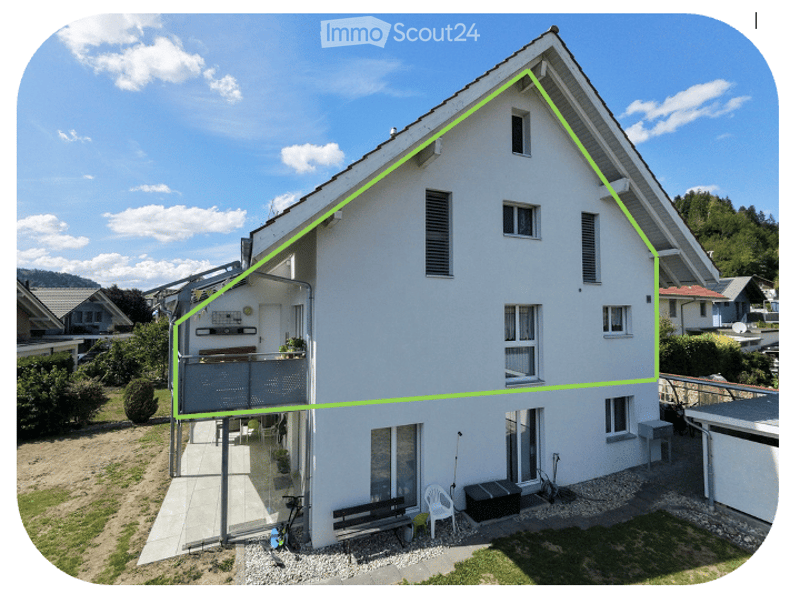 Single-family house with white exterior, multiple windows, and a small balcony area with outdoor furniture.
