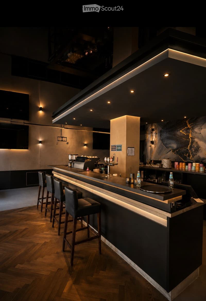 Modern bar area with a sleek black and white counter, bar stools, coffee machine, beer tap, and various bottles and cups on the counter.