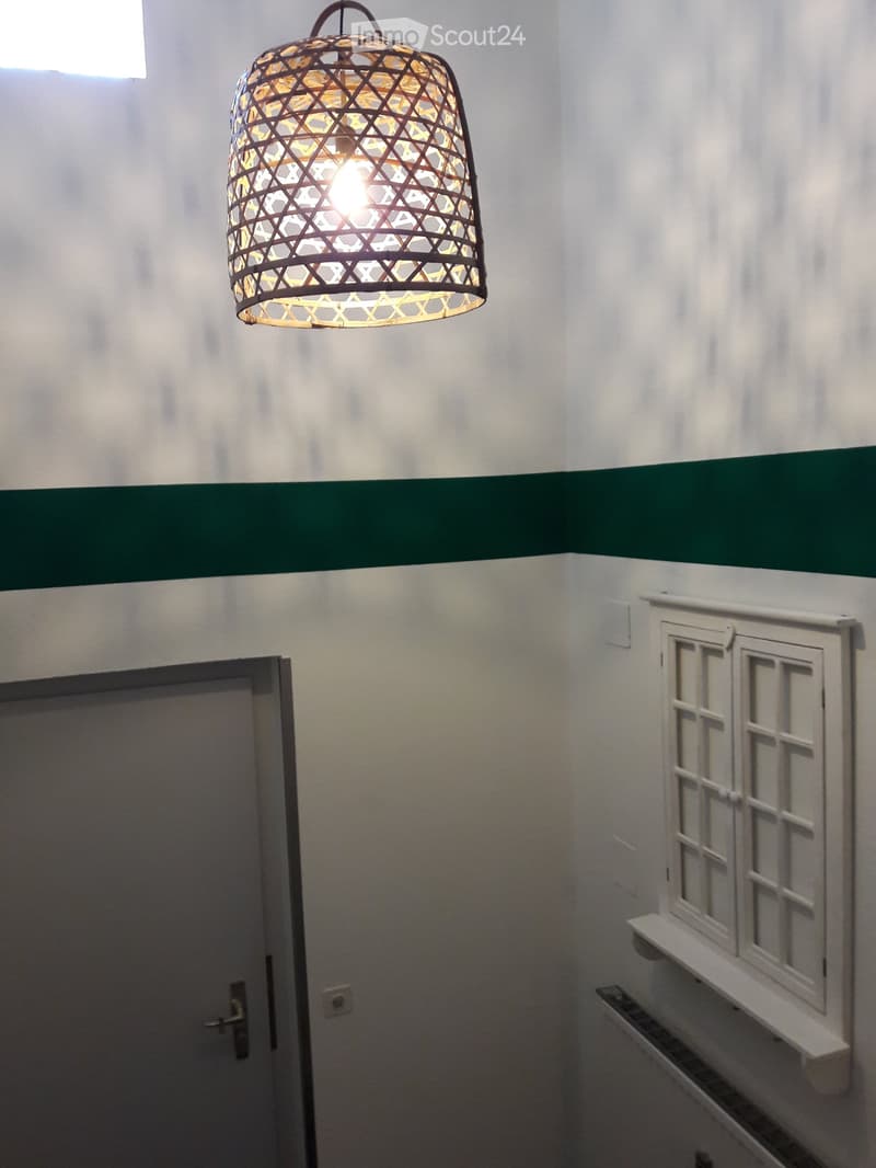 wall with green stripe, hanging light, white door, window with small wooden shutters