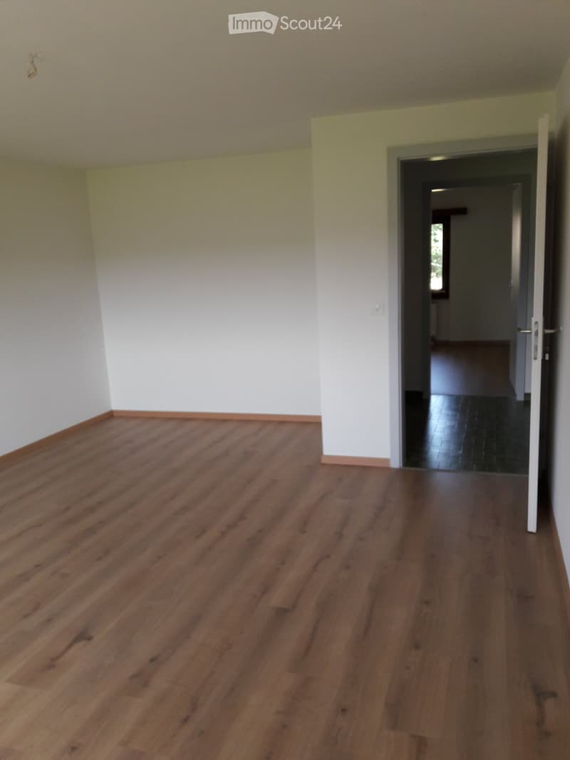 empty room, wooden floor, white walls, open door, hallway leading to another room