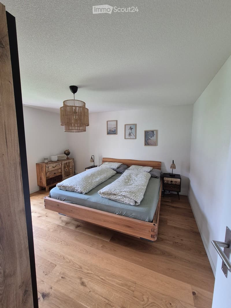 Cozy bedroom with wooden bed, nightstands, pendant light, and artwork on the wall.