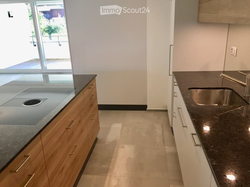 Modern kitchen with dark granite countertops, wooden cabinets, and a stainless steel sink.
