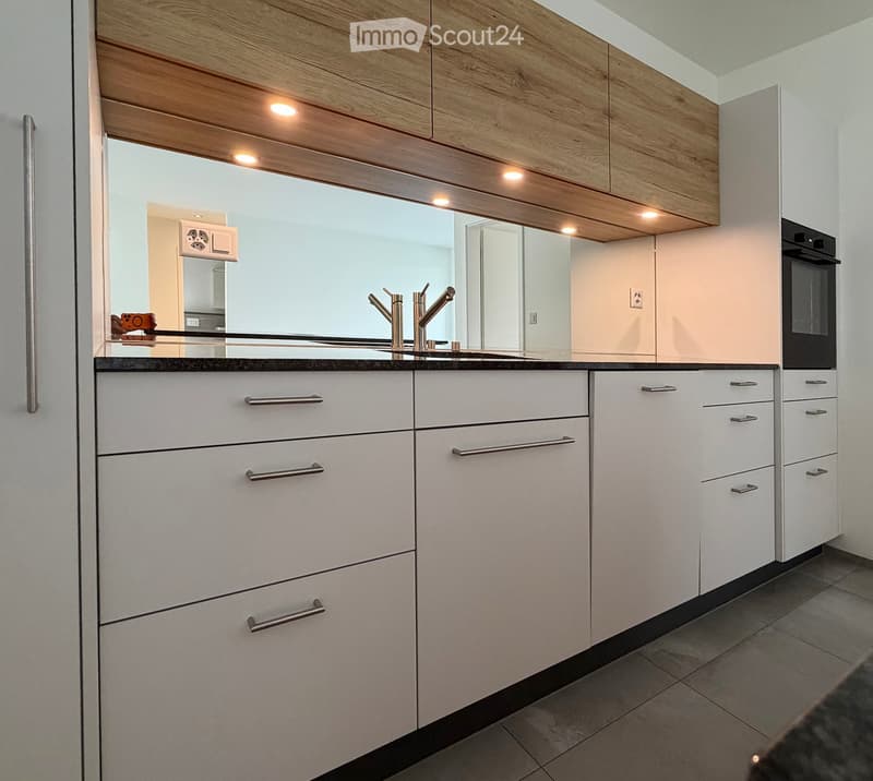 Modern kitchen with white cabinets, stainless steel handles, and a sleek sink with a modern faucet.
