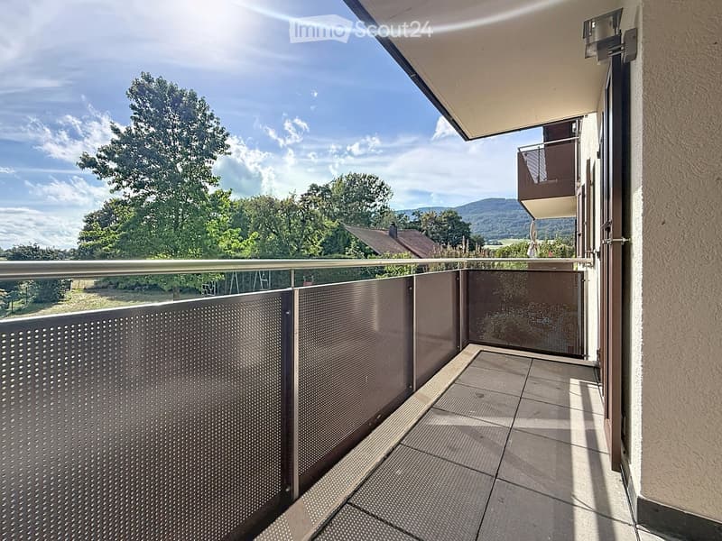 Balcony with metal railing, tiled floor, and scenic view of trees and hills.