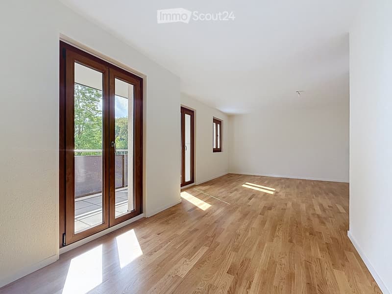 Empty room with wooden flooring, white walls, and large sliding glass doors leading to a balcony.