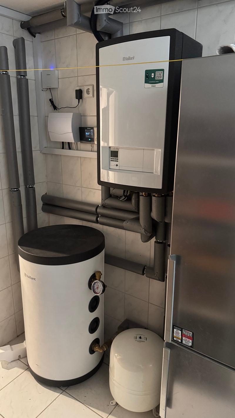 Utility room with a Vaillant water heater, pressure tank, control unit, and gauge on tiled walls.