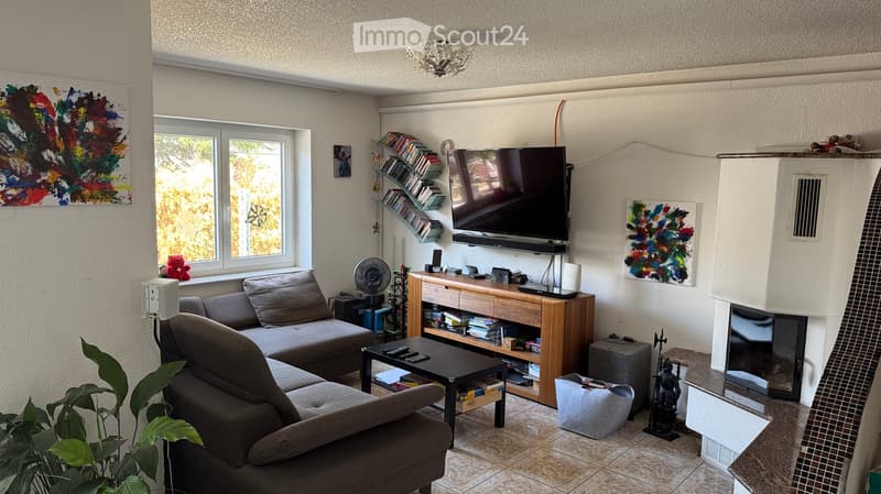 Living room with a grey sectional sofa, coffee table, TV, fan, bookshelf, and fireplace.