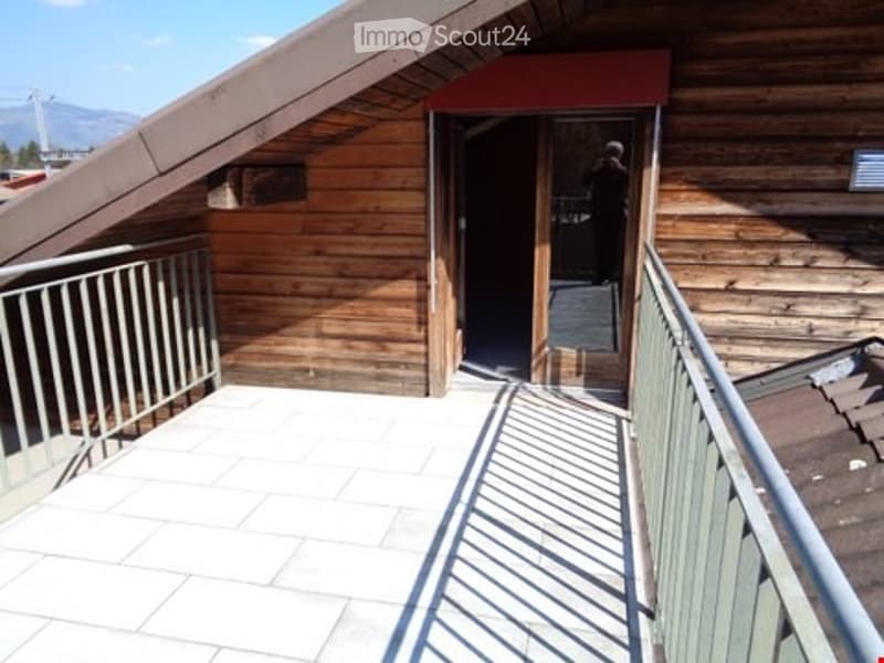 Wooden balcony with metal railing, tiled floor, and access door to interior space.